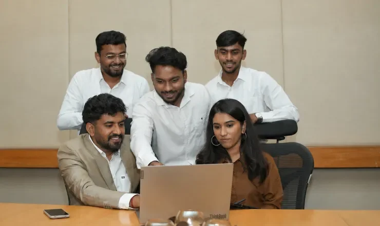 Appac Media team discussing project around laptop